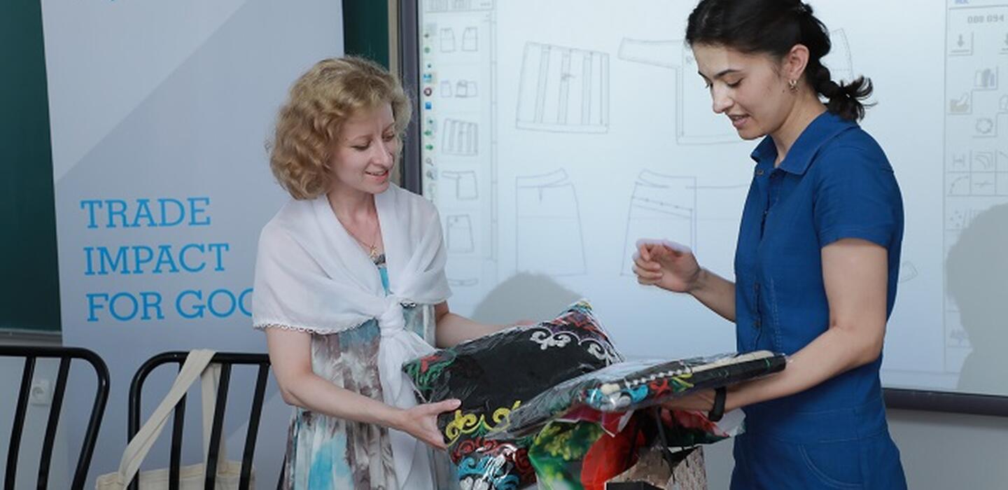 Two women looking at handicrafts with an ITC banner in the background